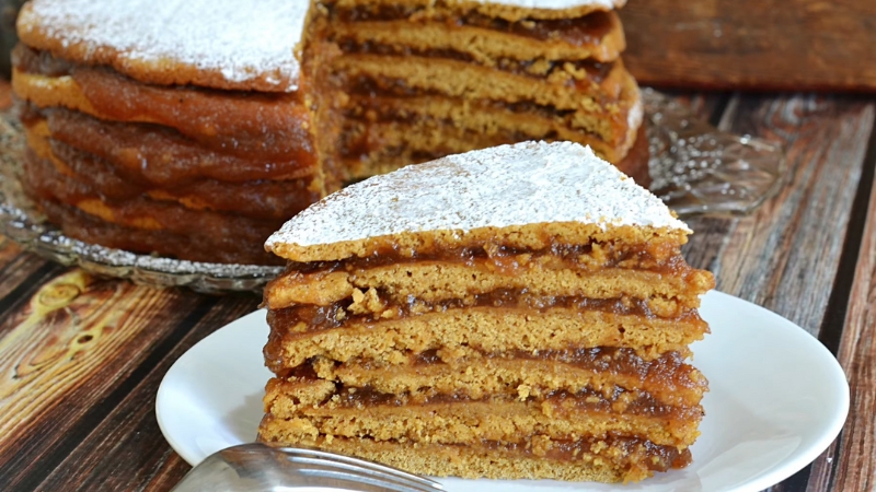 A slice of apple stack cake with apple filling and powdered sugar on top